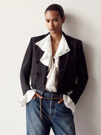 Front view of the A.L.C. Colette Top in Ivory under a black tuxedo jacket with jeans and a chain belt.