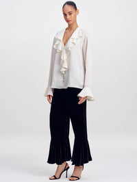 Three-quarter full-length view of the A.L.C. Colette Top in Ivory with black velvet flared pants and heels.