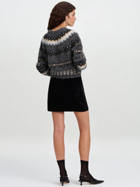 Back full-length view of the A.L.C. Petra Velvet Mini Skirt in Black styled with a cropped grey sweater.