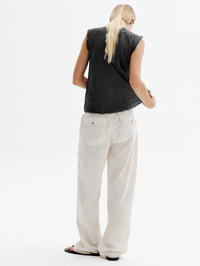 Back view of the Iris Gauze Tank in black by ALL THREE, paired with cream wide-leg pants