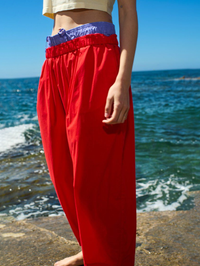 Side view of the Bailow Pant in Fraise Vintage red by American Vintage, styled at the beach