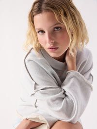 Seated view of the American Vintage Dantown Pullover in Melange Sky Blue showing the raw edge seams