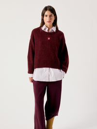 Model wearing the American Vintage East sweater in Melange Acerola with burgundy trousers