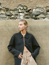 Styled view of the BOLOLA NYC Lola Bolo in Gold with Tigers Eye against a stone wall.