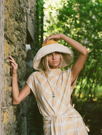 Styled shot of the BOLOLA NYC Merriam Bolo in Gold with Malachite worn with a sun hat.