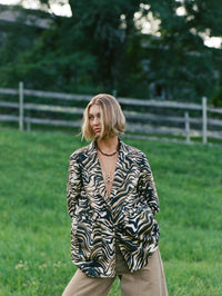Model wearing the BOLOLA NYC Merriam Bolo in Gold with Tigers Eye under a zebra print blazer.