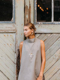 Side view of the BOLOLA NYC Palmette Bolo in Silver with Citrine worn against a wooden door.