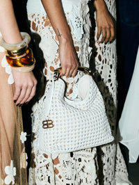 Backstage shot of the Bronx and Banco braided leather shoulder bag in White held against a lace skirt.