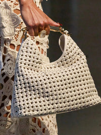 Close-up of the Bronx and Banco woven leather shoulder bag in White carried by its gold top handle.