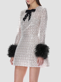 Front view of the silver sequined mini dress with black bow detail and feather cuffs by BRONX BANCO