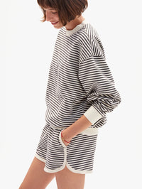 Side view of the Le Jogging Short in black and cream stripes by CLARE V., styled with matching striped sweatshirt