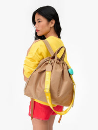 Back view of the Sac Tout Back Pack in latte by CLARE V. with yellow straps and turquoise accent charm
