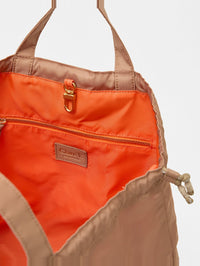 Close-up of the coral-lined Sac Tout Back Pack in latte by Clare V. with branded label