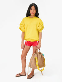 Full-length view of the Sac Tout Back Pack in latte by Clare V., styled with a yellow sweatshirt