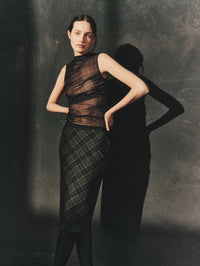 Editorial view of the Enza Costa Plaid Mesh Sleeveless Twist Top in Shadow Plaid with a plaid midi skirt.