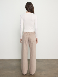 Back view of cream long-sleeve fitted top styled with beige wide-leg denim jeans