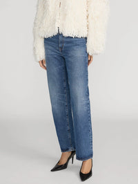 Side view of the FRAME The Hang straight-leg jean in Lucky worn with black pointed pumps.