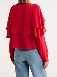 Back view of the FRAME Wrap Cape Blouse in Lipstick showing layered silk cape tiers and button cuffs.