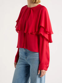 Side view of the FRAME Wrap Cape Blouse in Lipstick with ruffled cape layers falling over the sleeve.