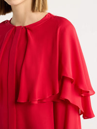 Close-up of the jewel neck and ruffled silk cape on the FRAME Wrap Cape Blouse in Lipstick.