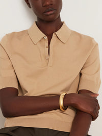 Model in a camel polo wearing the Jenny Bird Gemma Bangle in high polish gold.