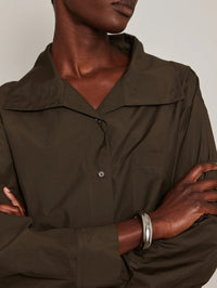 Model in an olive shirt wearing the Jenny Bird Gemma Bangle in platinum with arms crossed.