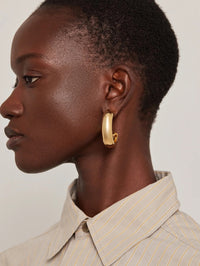 Side profile of a model wearing Jenny Bird Large Gia Hoops in high polish gold.