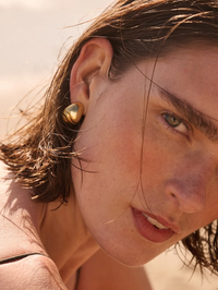 Close-up of High Polish Gold Nelle Hoops by Jenny Bird worn on model's ear with natural makeup