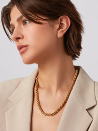 Side profile of the high polish gold Rizzo Necklace by Jenny Bird worn with a cream blazer
