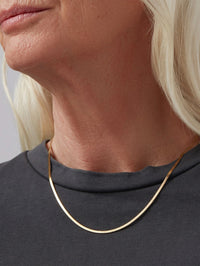 Close-up of the Jenny Bird Zeina Chain in gold worn at the neck over a grey tee.