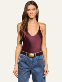 Front view of the L'AGENCE Lexi Silk Camisole in Deep Sangria tucked into belted printed jeans