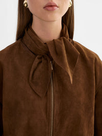Close-up of the tie-neck scarf and gold zip on the LAMARQUE Anita Suede Bomber Jacket in Brown.