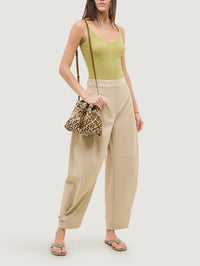 Model wearing the NAGHEDI Gramercy Bucket Double Weave in Carmel over the shoulder with a green tank.