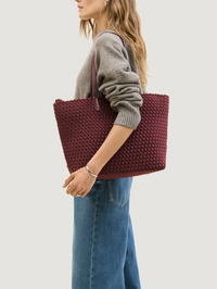 Side view of the bordeaux Jetsetter Small Tote with woven texture by NAGHEDI, styled as a shoulder bag