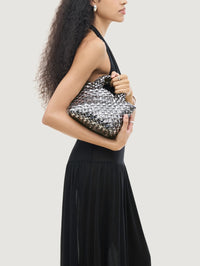 Model holding the NAGHEDI St. Barths Petit Tote Double Weave Metallic in Pewter under her arm.