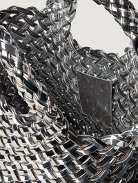Interior close up of the NAGHEDI St. Barths Petit Tote in Pewter showing the metallic woven handles and tag.