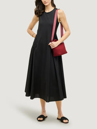 Model wearing the NAGHEDI St. Barths Petit Tote in Rosso crossbody over a black midi dress.