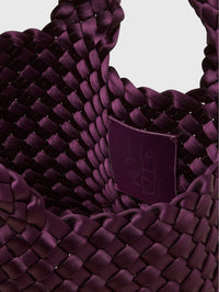 Interior close up of the NAGHEDI St. Barths Petit Tote Satin in Bisou with its embossed logo patch.
