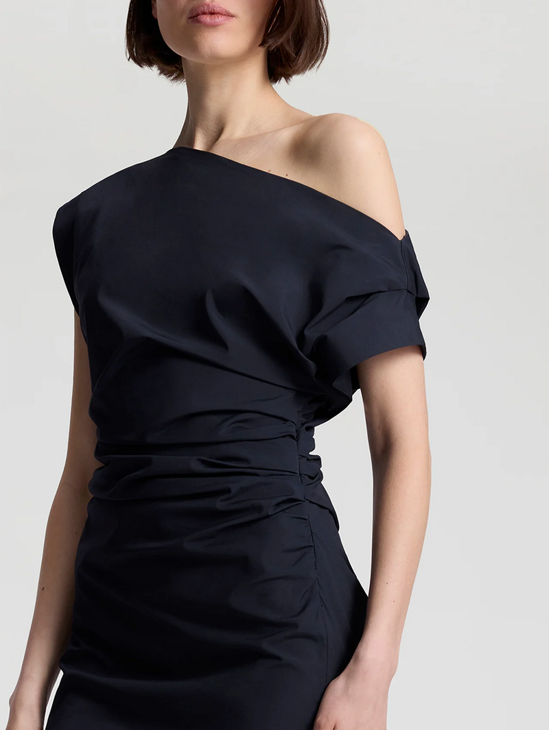 Woman wearing a black off-shoulder top against a light gray background