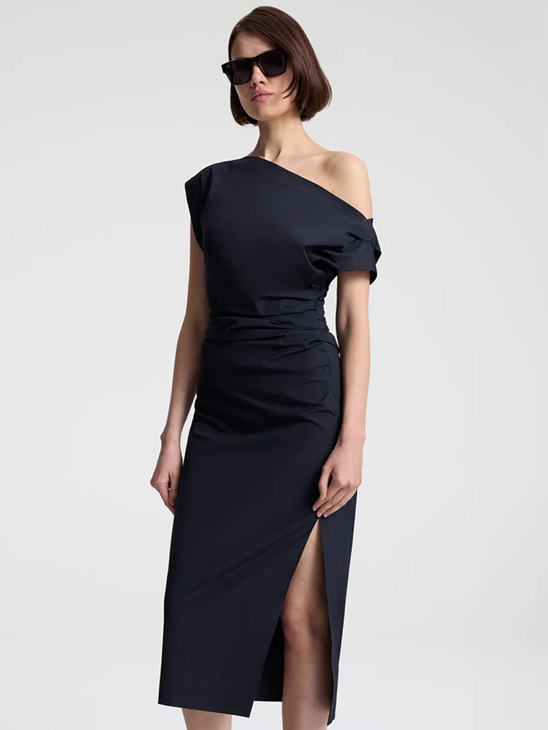 Woman wearing a black one-shoulder dress with a slit on a white background