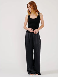 Full length view of the SABLYN Coco Scoop Neck Tank in Black styled with wide leg silk pants