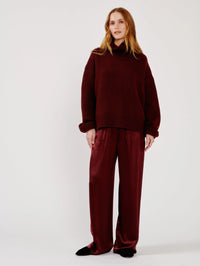Full length front view of the SABLYN Scarlett Slouchy Mock Neck Sweater in Cabernet with satin wide leg pants