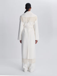 Back view of the SIMKHAI Carrie Fringe Coat in Frost showing fringe across the collar and hem.