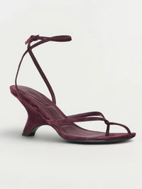 Three-quarter front view of the SIMKHAI Kelsey Suede Strappy Wedge in fig with its sculpted shadow heel.