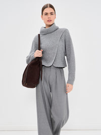 Styled view of the SIMKHAI Orlienne turtleneck in Grey Melange with grey pleated trousers.