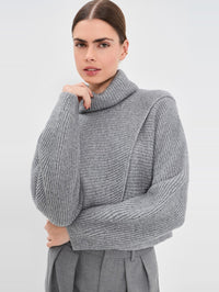 Detail view of the asymmetrical seam on the SIMKHAI Orlienne turtleneck sweater in Grey Melange.