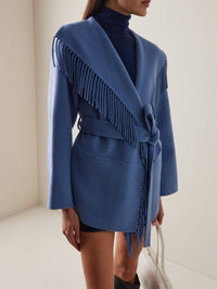 Model wearing the SIMKHAI Rowen Fringe Jacket in Dusty Frost, belted at the waist with fringe down the front.