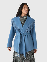 Front view of the SIMKHAI Rowen Fringe Jacket in Dusty Blue, belted over a plaid dress.