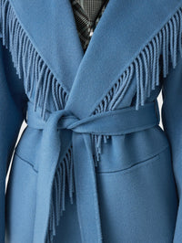 Close-up of the fringed shawl collar and tied belt on the SIMKHAI Rowen Fringe Jacket in Dusty Blue.