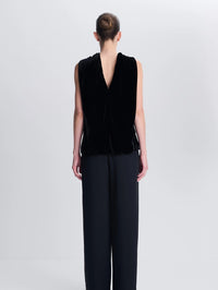 Back view of a model wearing the SIMKHAI Scarlett Draped Velvet Cape Top in Black with its open back drape.